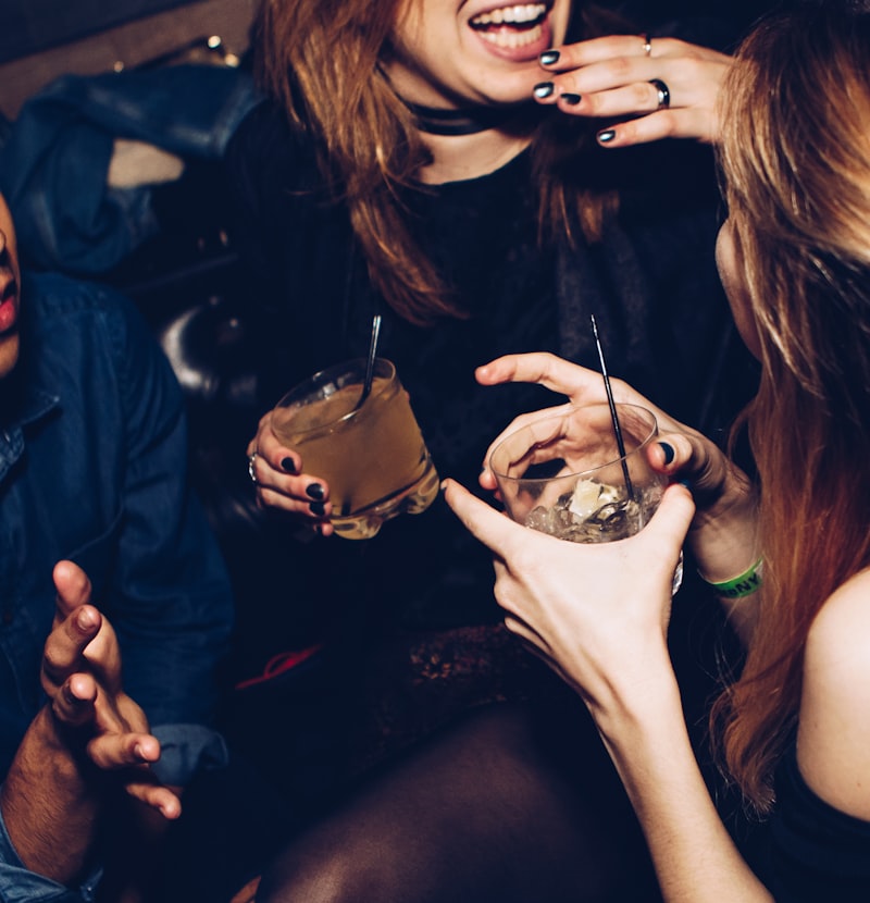 Menschen in einer Bar unterhalten sich und halten Getränke in der Hand.