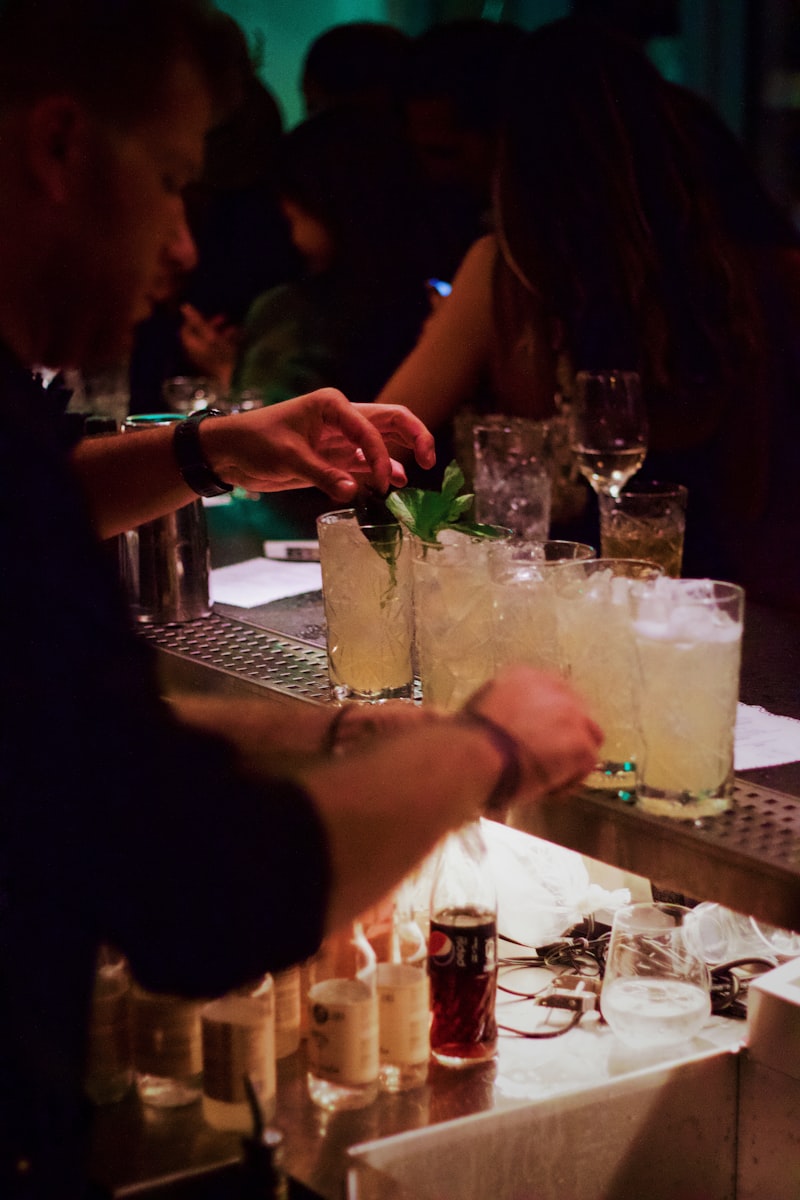 Barkeeper bereitet Cocktails mit Minzgarnitur an einer belebten Bar vor.