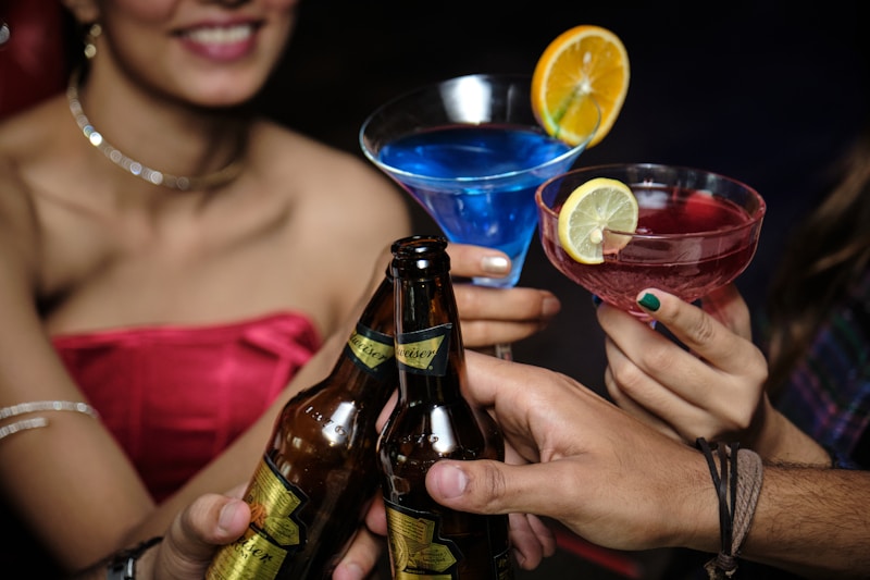 Personen stoßen mit Getränken, darunter Cocktails mit Orangen- und Zitronenscheiben, an.